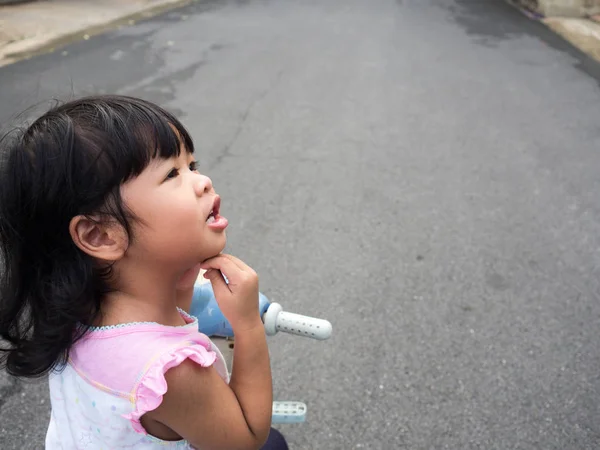 Asian girls ride a bicycle and thinking, Her face looks suspect and has questions. — Stock Photo, Image