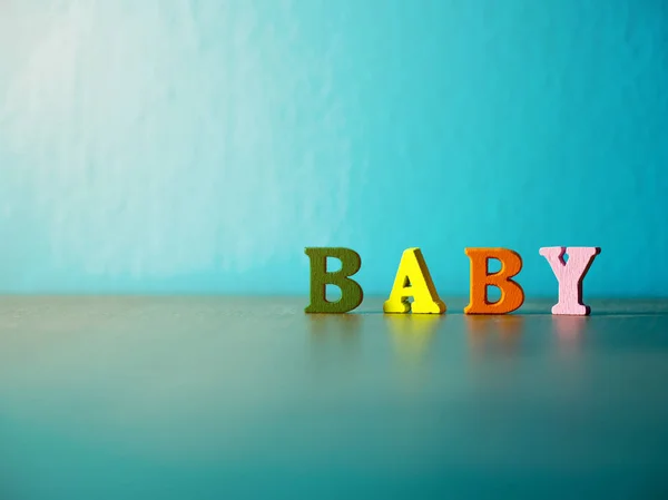 Baby. English alphabet made of wooden letter color. Alphabet baby on wooden table and background is powder blue. — Stock Photo, Image