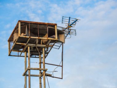 Eski halk hoparlörleri yüksek kulede mavi gökyüzü arka planında vintage yayın yapıyor.