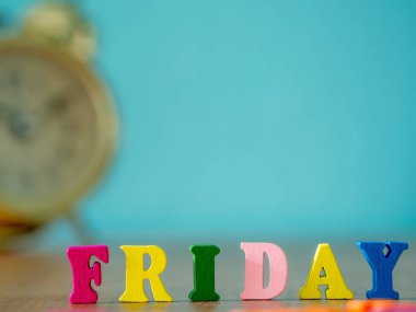 Renkli ahşap Cuma günü ahşap masa ve vintage çalar saat ve arka plan açık mavi bir kelimedir. İngilizce alfabe ahşap mektup rengini yapılan.