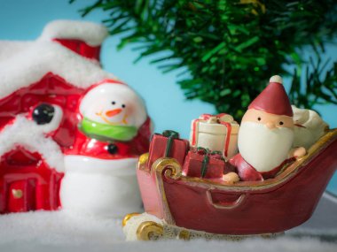 Mutlu Noel Baba hediye kutusu bahçesine gitmek kar kızağı üzerinde. Evin yakınına kardan adam ve Noel ağacı var. Noel Baba ve ev kar üzerinde. Noel ve mutlu yeni yıl kavramı.
