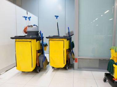 Temizlik arabası istasyonunda. Temizlik araçları sepeti ve sarı paspas kovası temizlik için bekleyin. Kova ve Havalimanı ofisi ekipman temizleme seti.