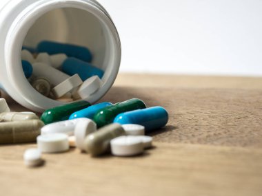 Necklac ilaç ve kapsül üzerinde ahşap tablodur. Portre. Uyuşturucuya karşı olduğumuzu sağlık için kapsayıcısında (ilaçlar), tedavi. Yeşil mavi beyaz yuvarlak kapsül hap ilaç antibiyotik ile yığını