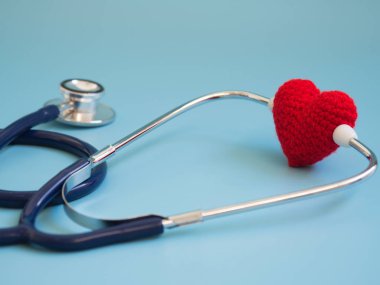 Kırmızı kalp mavi arka plan üzerinde koyu mavi stetoskop kullanarak. Sevgi ve bakım hasta tarafından kalp kavramı. Kopya alanı metin ve içeriği için