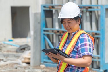 Bina ve evler önce yerlerde doğruluğu kontrol etmek için tablet kullanarak bina site üzerinde Asya kadın işçi ve mühendis.