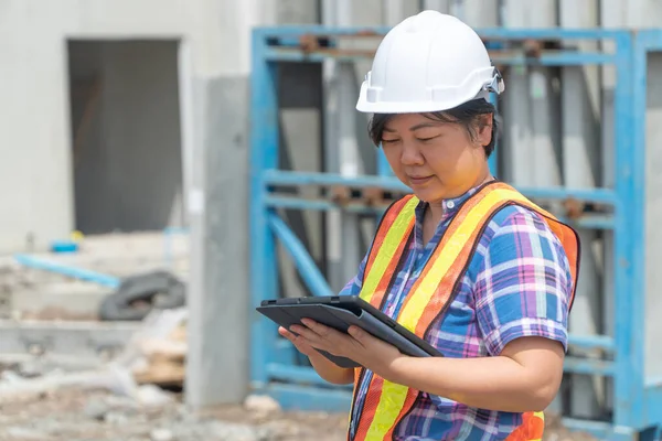 Bina ve evler önce yerlerde doğruluğu kontrol etmek için tablet kullanarak bina site üzerinde Asya kadın işçi ve mühendis.