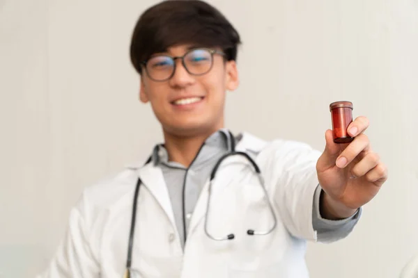 Azjatycki Lekarz Stetoskopem Mundurem Trzymający Butelkę Lekiem Wyjaśniający Właściwości Lecznicze — Zdjęcie stockowe