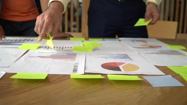 Gruppo di uomini d'affari in piedi incontro con i colleghi in sala riunioni e visualizzare il grafico delle prestazioni annuali Per analizzare e anticipare le tendenze di business. Concetto di successo aziendale con il lavoro di squadra — Video Stock