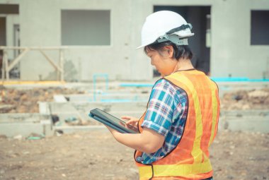Bina ve evler önce yerlerde doğruluğu kontrol etmek için tablet kullanarak bina site üzerinde Asya kadın işçi ve mühendis.