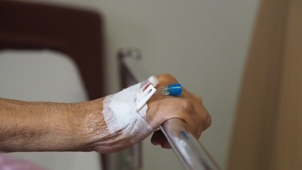 Primer plano paciente anciano mano del hombre con solución salina intravenosa (iv) en el hospital. paciente con tapón de aguja para uso con medicamentos a la solución salina . — Vídeos de Stock
