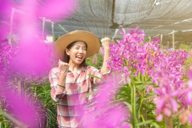 genç kadın bahçıvanlar ekose gömlek giymek ve bir şapka giymek. Eller yumruğu kaldırın ve neşe ve gülümseme ifade edin. yeni nesil çiftçi, bahçıvanlar kavramı.