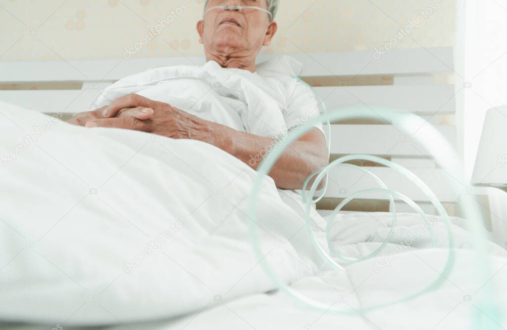 Sad senior man lying on the hospital bed and with a nasal breathing tube for treatment respiratory. Concept of Health care for the elderly, quarantine coronavirus (COVID-19)