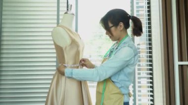 Asyalı kadın terzi moda tasarımcısı galeride manken boyutunda. Terzilik ve moda kavramı