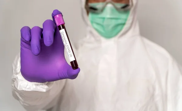 Doctors in the protective suits and masks are holding a positive blood test result for new rapidly outbreaking Coronavirus. Concept of spreading Coronavirus (COVID-19) around the world, USA, Europe