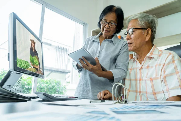 Asian senior couple using tablet and computer for shopping online on the internet at home. Concept of new normal lifestyle, Social distancing for prevention outbreak coronavirus