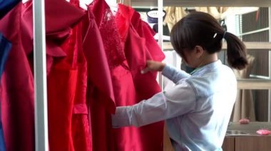 Mutlu Asyalı kadın terzi moda tasarımcısı bir elbise ve galeride elbise için hazırlık yapıyor. Başarı kavramı Moda sektöründeki genç girişimci.