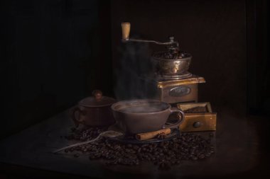 Kahve çekirdekleri, eski bir kahve değirmeni ve bir fincan sıcak kahve ile natürmort