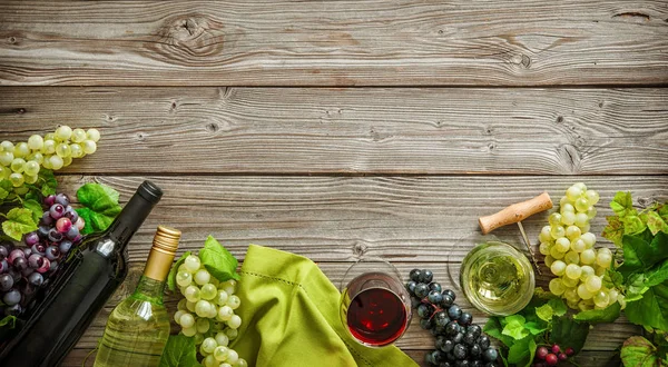 Botellas de vino con uvas y corchos sobre fondo de madera — Foto de Stock