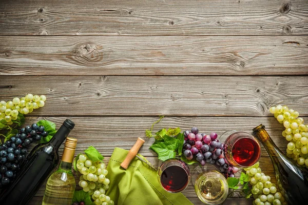 Винні пляшки з виноградом і пробками на дерев'яному фоні — стокове фото