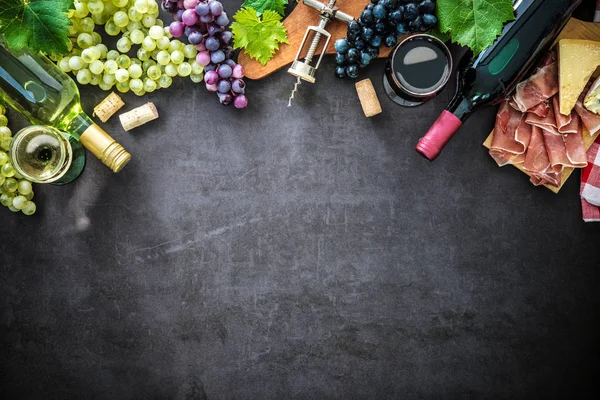 Garrafas de vinho com uvas, queijo, presunto e rolhas — Fotografia de Stock