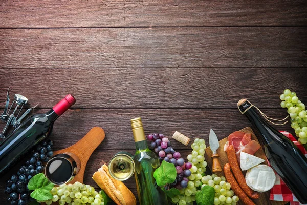 Wine bottles with grapes, cheese, ham and corks — Stock Photo, Image