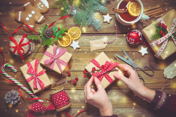 Mãos femininas embrulhando Natal férias presentes artesanais em papel artesanal com fita — Fotografia de Stock