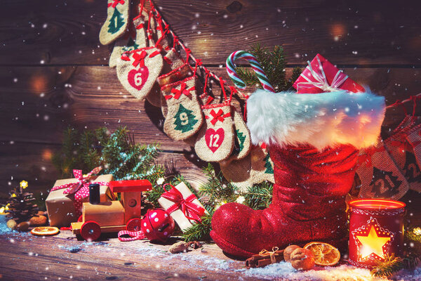Advent calendar and Santa's shoe with gifts on rustic wooden bac