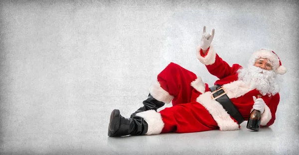 Feliz Papai Noel deitado no chão com uma garrafa de vinho — Fotografia de Stock