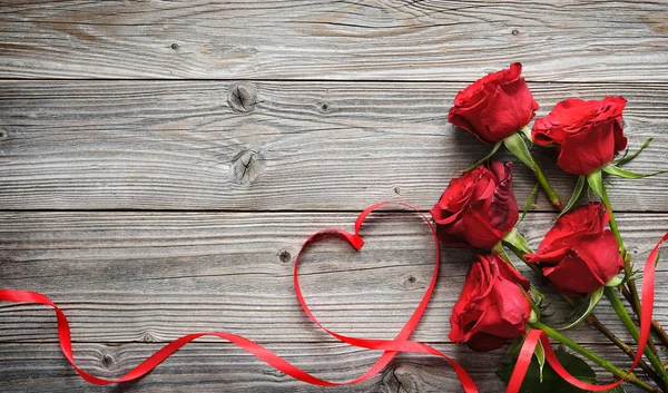 Romantica cornice floreale con rose rosse e nastro su fondo in legno — Foto Stock