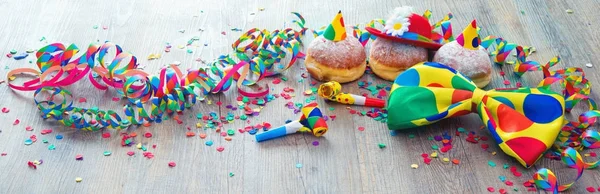 Carnival donuts with paper streamers and party bow tie — Stock Photo, Image