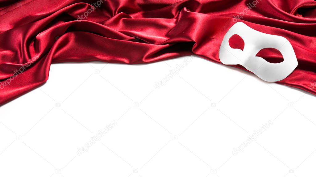 White theatre mask on red silk fabric