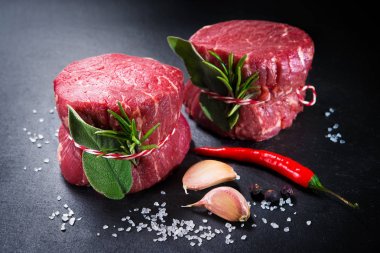 Raw beef fillet steaks mignon on dark background clipart