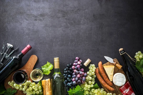 Garrafas de vinho com uvas, queijo, presunto e rolhas — Fotografia de Stock