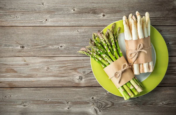 Mazzi di asparagi freschi verdi e bianchi su fondo di legno — Foto Stock