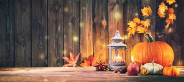 Meyveli balkabakları ve dökülen yapraklar kırsal ahşap masada.