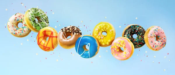 Vários donuts coloridos em movimento no fundo azul — Fotografia de Stock