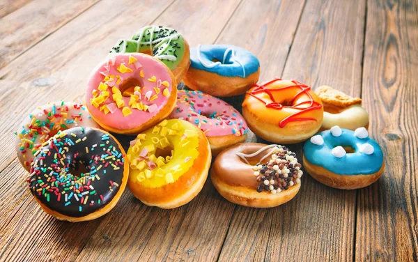 Varios donuts de colores en madera —  Fotos de Stock