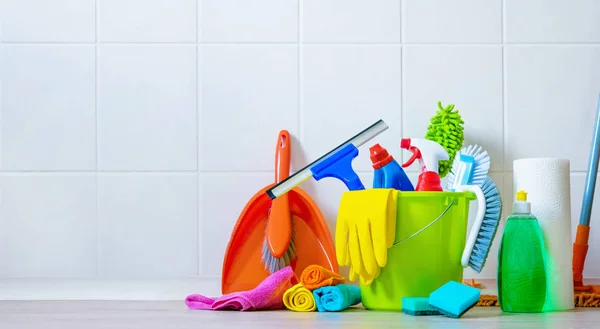 Emmer met schoonmaakbenodigdheden aan de voorkant van de betegelde wand — Stockfoto
