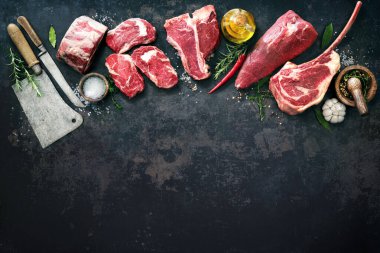 Köy tahtasında baharat ve çatal bıçaklarla ızgara yapmak için çiğ et bifteği çeşitliliği.