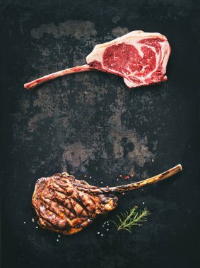 Kara angus Tomahawk bifteği çiğ ve koyu kırsal arka planda baharatlı ızgara.