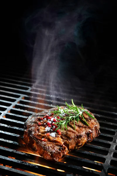 Beef steak on the grill with smoke and flames