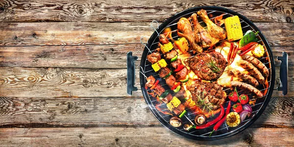 バーベキューグリルの上に煙と素朴な木製の板に炎で野菜と各種おいしいグリル肉のトップビュー — ストック写真