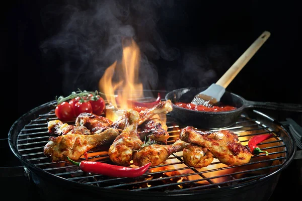 熱い炎のバーベキューグリルで鶏の足やドラムスティックを焦げ煙を背景にグリル — ストック写真