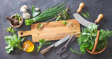 Bahçeden çeşitli taze otlar ve kırsal masada mutfak aletleri. Kopyalama alanı olan üst görünüm