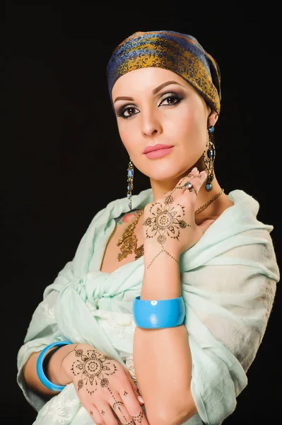 Oriental woman in a scarf with a picture of henna in her arms in the studio — Stock Photo, Image