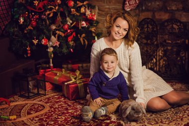 mutlu anne ve oğlu bir Noel ağacı ve bir şömine yakın oturan