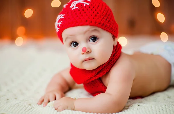 kırmızı bir Noel şapkalı küçük çocuk beyaz kürk halı üzerinde yatıyor