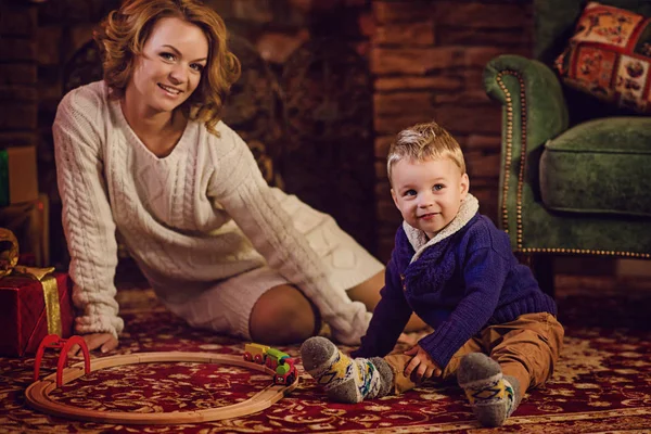 mutlu anne ve oğlu bir Noel ağacı ve bir şömine yakın oturan