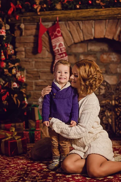 mutlu anne ve oğlu bir Noel ağacı ve bir şömine yakın oturan