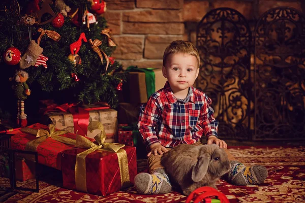 bir Noel ağacı ve bir şömine yakın oturan ve bir yeni yıl için bekleyen küçük çocuk